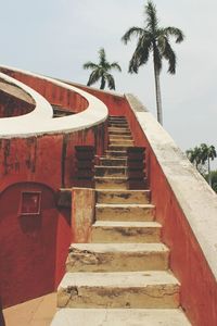 Steps by palm trees against sky