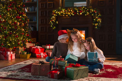 Rear view of woman sitting by christmas tree