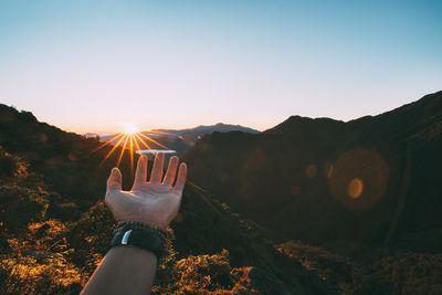 Person on mountain against sky during sunset