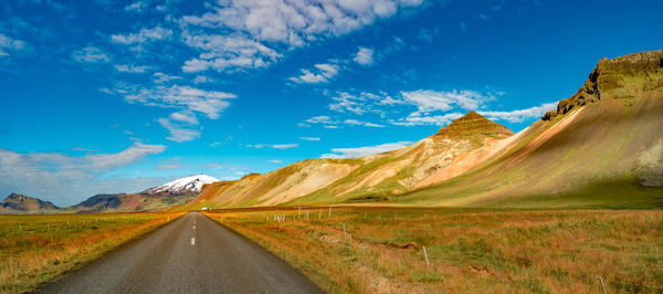 Road leading towards mountains against sky