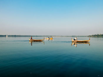 People in boat on sea against clear sky