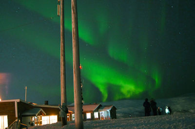 People standing by illuminated building against sky at night