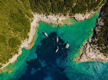 Scenic view of sea and rocks in blue bay with sailing yachts at anchor.
