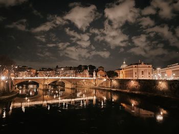 Illuminated bridge over river against sky at night