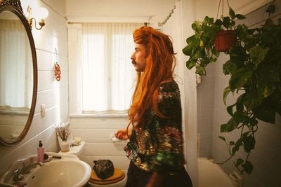 Side view of young woman standing at home