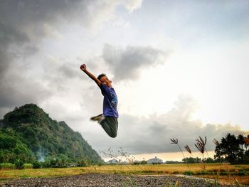 Man jumping on field against sky