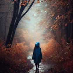 A girl walks through the autumn forest in a the rain