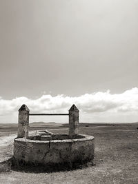 Old ruin on field by sea against sky