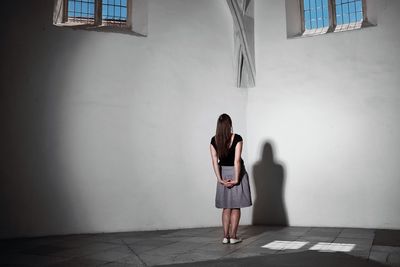 Rear view full length of woman standing against wall in church