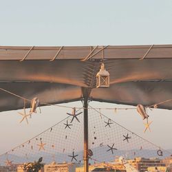 Low angle view of birds hanging on roof against clear sky