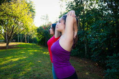 Female friends looking away while exercising at park