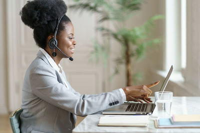 Side view of businesswoman using laptop on table