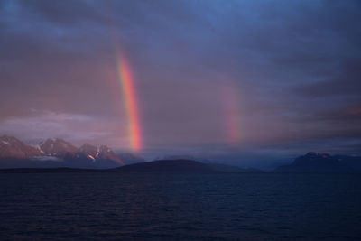 Scenic view of rainbow over mountains against sky during sunset