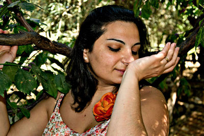 Mid adult woman with eyes closed standing by trees at park