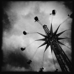 Low angle view of ferris wheel against cloudy sky