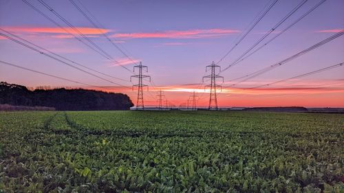 Electricity pylon on field against sky during sunset