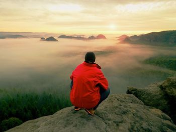 Silhouette of young confident and powerful man standing with hands on hips, hidden sun. 