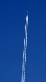 Low angle view of vapor trails against blue sky