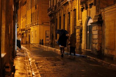 Rear view of woman walking on wet street at night