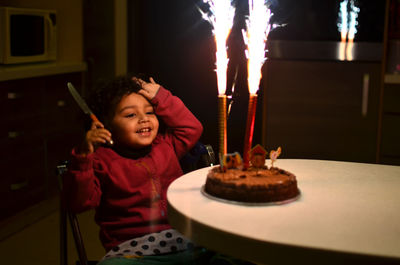 Girl looking at birthday cake while sitting at home