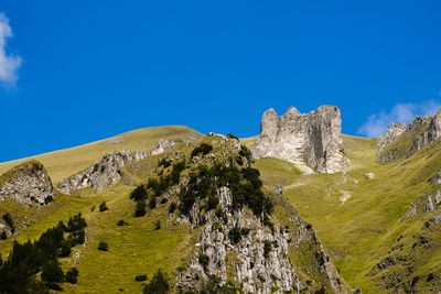 Low angle view of rocks against blue sky