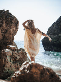 Rear view of woman at beach against clear sky