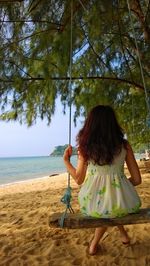 Rear view of woman relaxing on tree