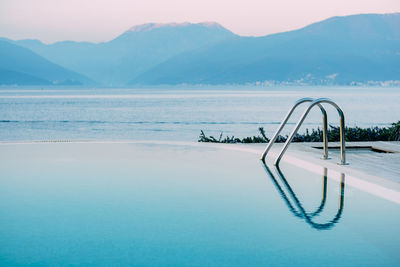 Scenic view of swimming pool by sea against mountains