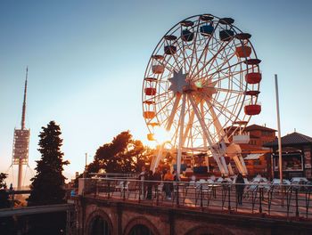 Ferris wheel in city against sky during sunset