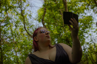 Portrait of young woman exercising against trees