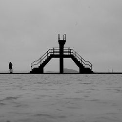 Silhouette man by sea against clear sky
