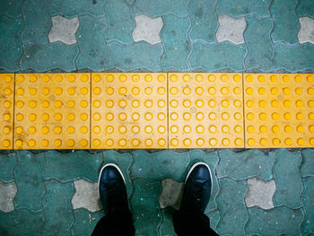 Low section of person standing on yellow wall