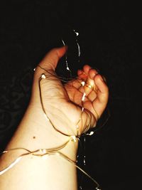 Close-up of hand holding ring against black background