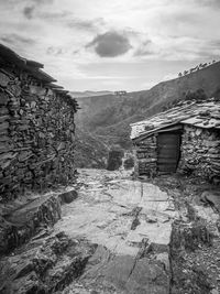 Abandoned house by mountain against sky