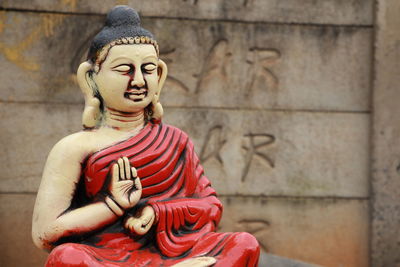 Statue of buddha against wall of building