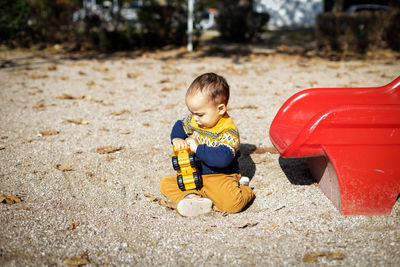 Funny baby boy playing at outdoors playground. toddler plays with toy car. sunny day