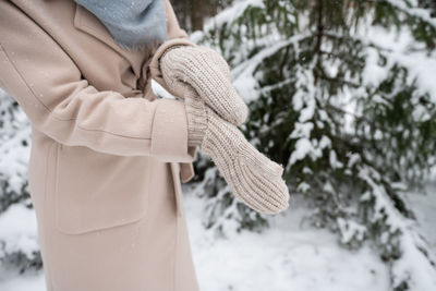 A girl puts on knitted mittens on the street in winter