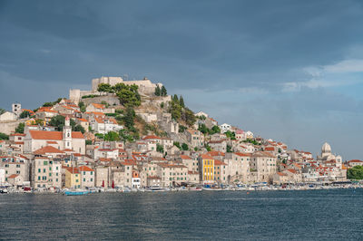 Buildings by sea against sky