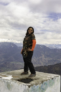 Happy traveler woman with smile on face standing at the top of water storage tank