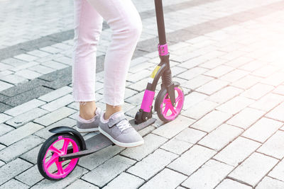 Low section of woman with pink umbrella on street