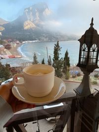 Coffee cup on table against mountains