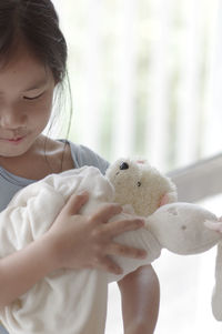 Cute girl holding teddy bear at home