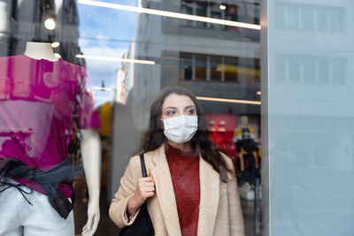 Woman wearing mask standing by clothing store