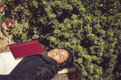 Close-up latin woman sleeping with a book in the garden