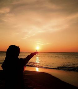 Silhouette man on beach against sky during sunset