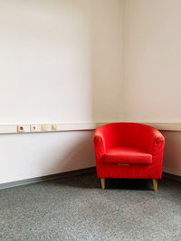Empty red chair against wall