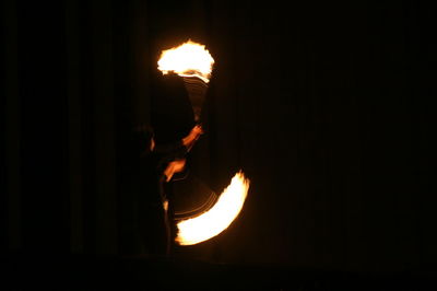 Silhouette man holding burning candle in dark