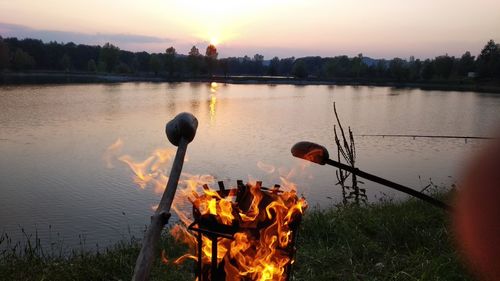 Scenic view of fire in lake against sky during sunset