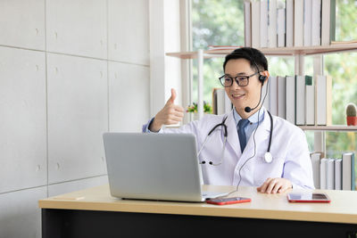 Smiling doctor gesturing while talking on video call at clinic