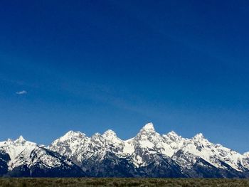 Scenic view of snowcapped mountains against clear blue sky